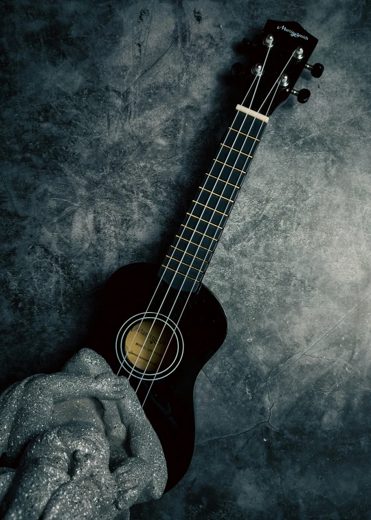 someone's hand holding an acoustic guitar against the grey background