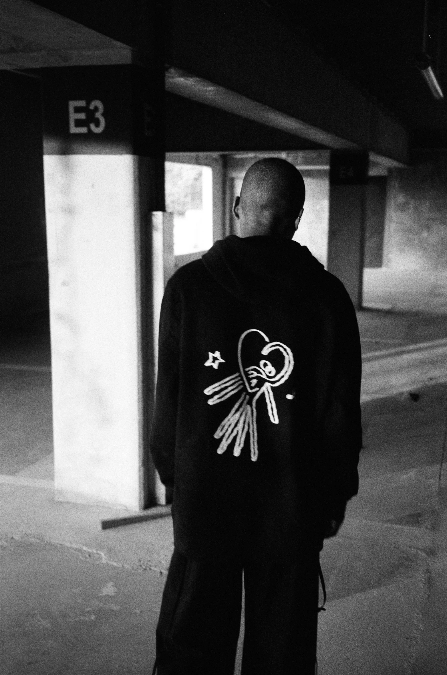 a man standing in front of a door wearing a hoodie