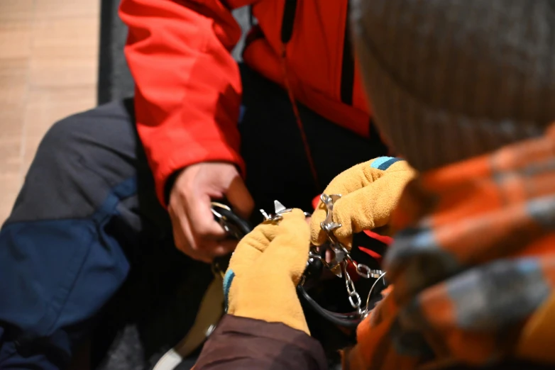 people with orange gloves on, one holding a chains