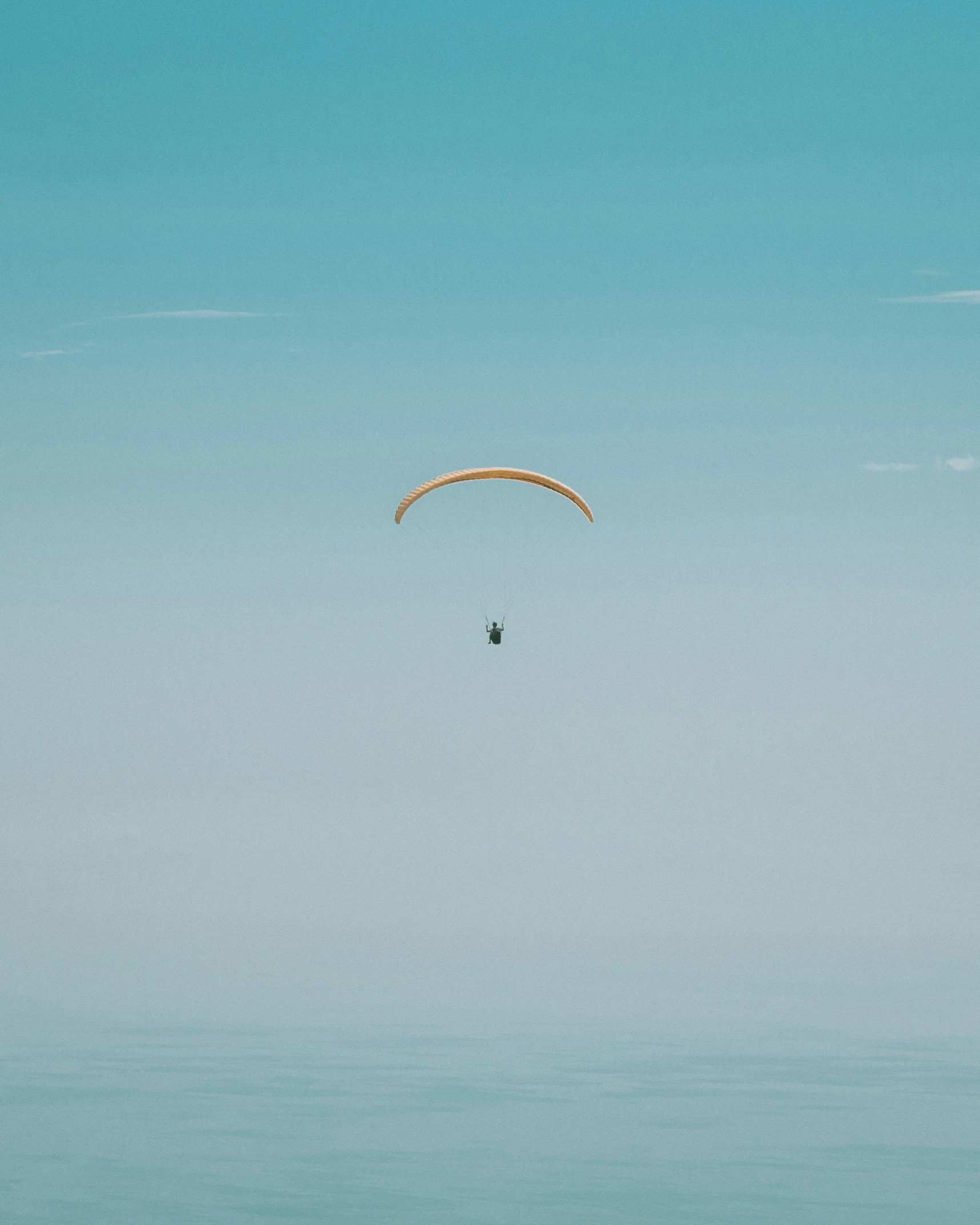 the person is parasailing through the clear blue sky