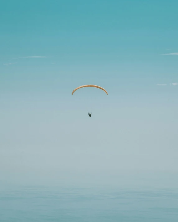 the person is parasailing through the clear blue sky