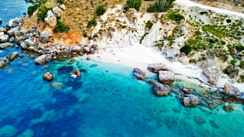 an aerial s of rocky coastline with clear blue water