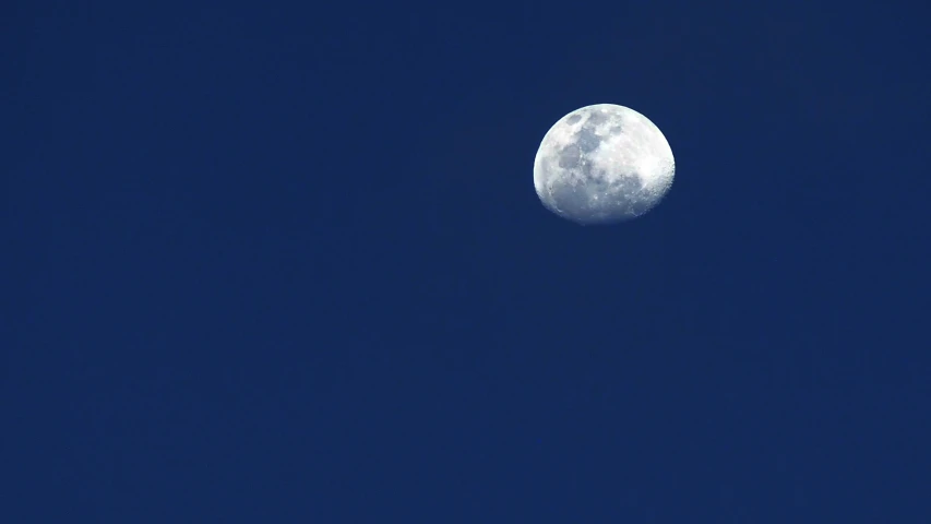 a small plane flying through the sky next to a very large moon