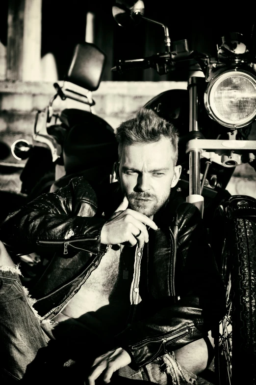 a man in a leather jacket sits on a motorcycle