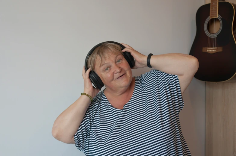 the woman is wearing headphones and listening to her guitar