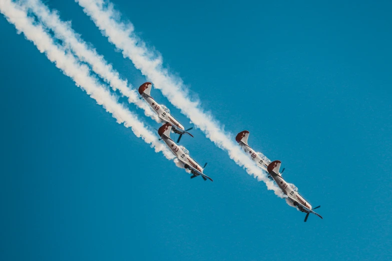 two jet airplanes flying through a blue sky and leaving trails