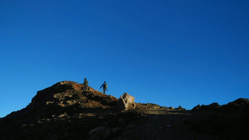 people standing on a rock ridge next to a hill