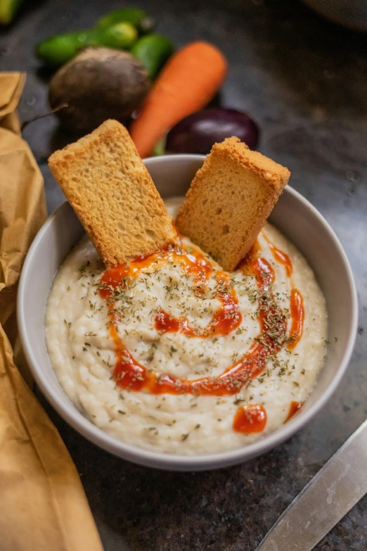 a bowl of soup on a table with toasted pieces of bread