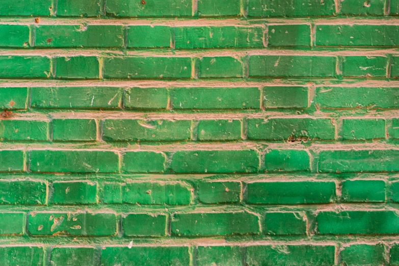 an old green brick wall with rusted paint