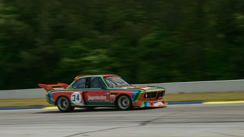 the rainbow - colored bmw racing car is turning around a corner