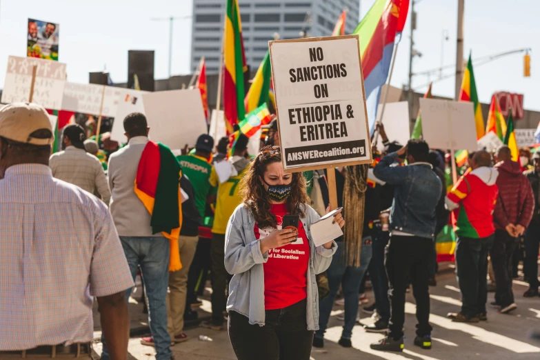 a young person holding a sign with some other people holding banners