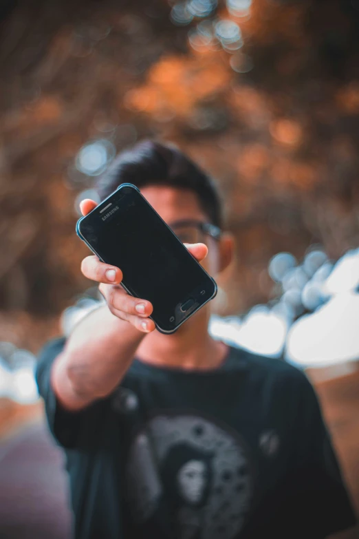 man holding up his cell phone and taking a po