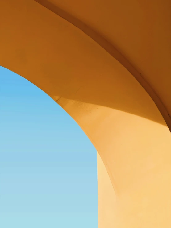 the sky is blue above an arch that has an orange wall