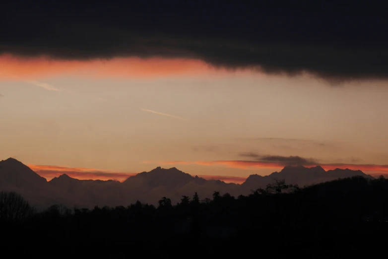 the clouds are reflecting the evening sky as a plane approaches