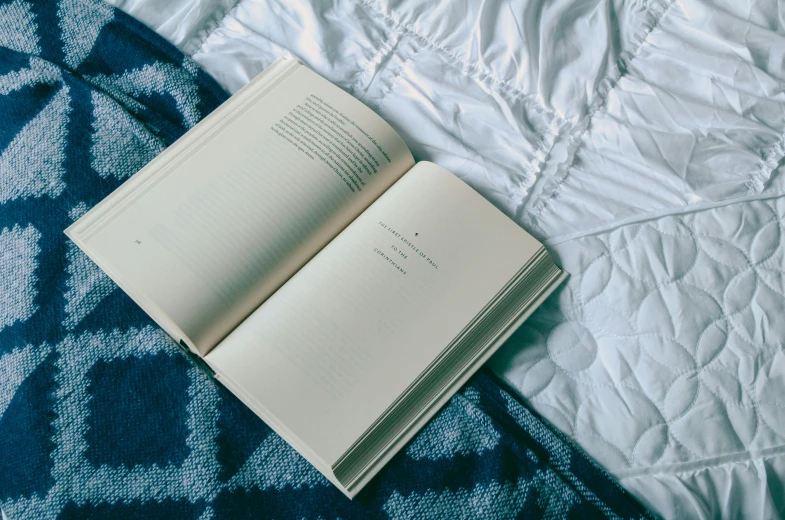 an open book laying on top of a bed