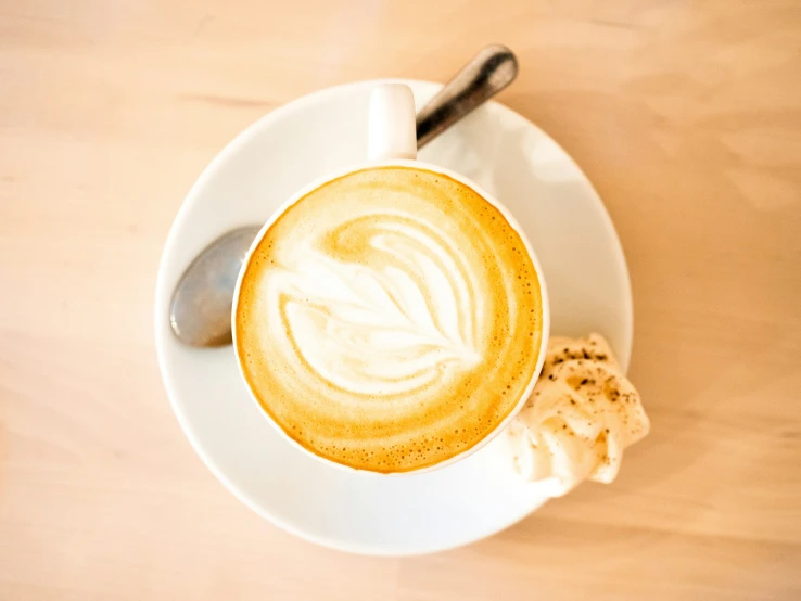 a cup of coffee with cream on top and a spoon near it