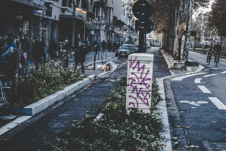 a sign has been graffitied on the sidewalk and on the curb