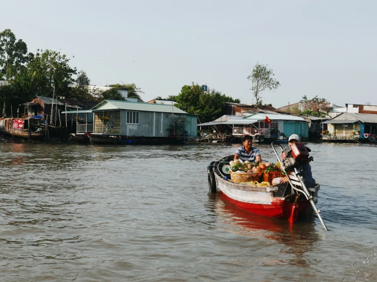 two people on a boat loaded with fruits and vegetables