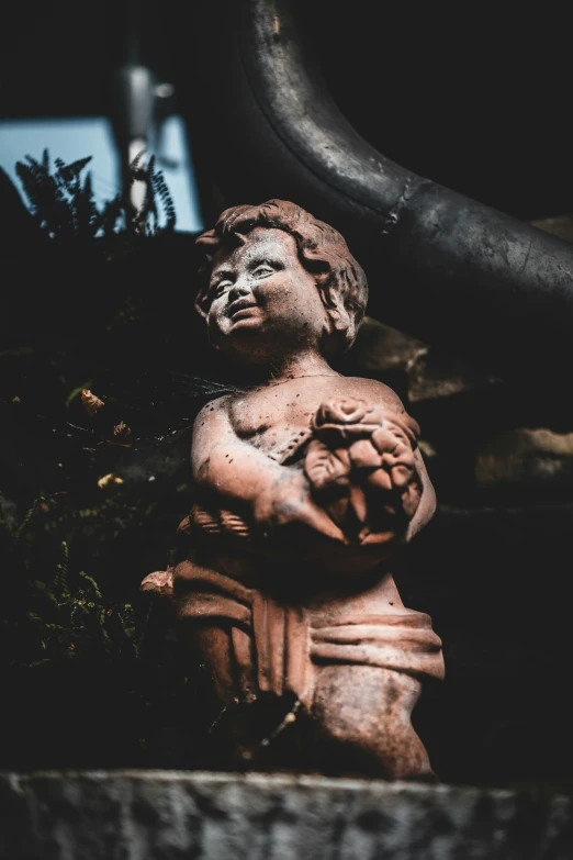 an old statue sitting in a planter with some dirt