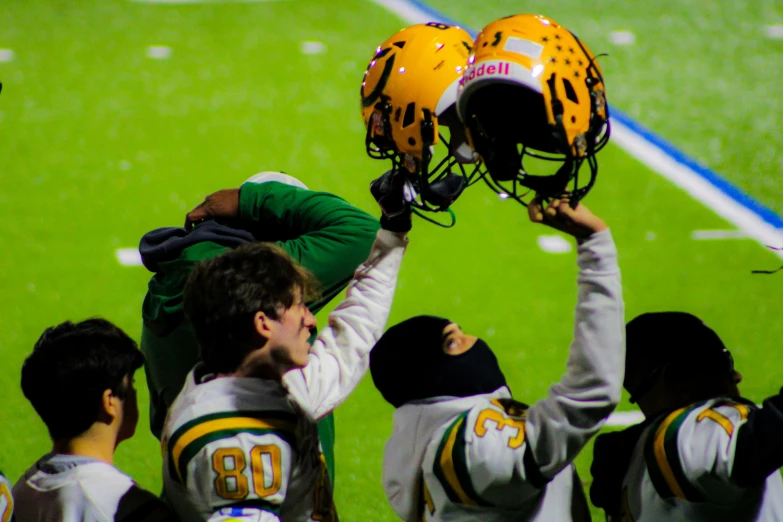 a football coach holding up a helmet on top of his head