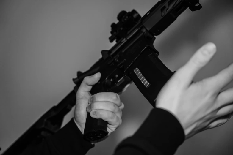 person holding and pointing to an automatic rifle