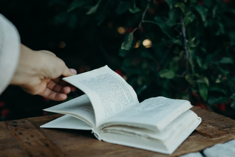 someone standing over a book open with pages pointing at it