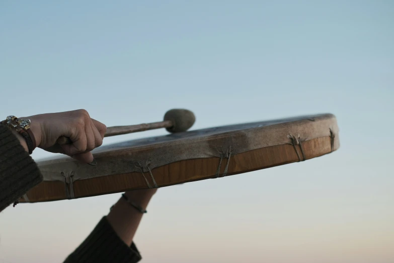 a man holding a large wooden object next to a beach