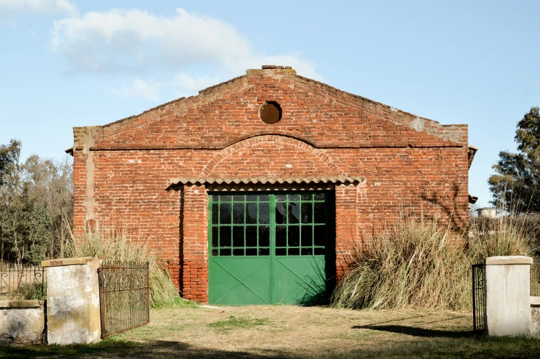 a green door is closed in an old red brick building