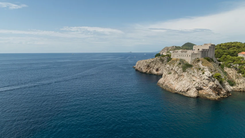 a stone castle sits atop a cliff overlooking the ocean