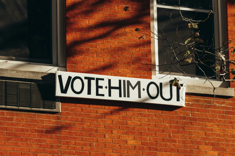 a sign that reads votemm out on a brick wall