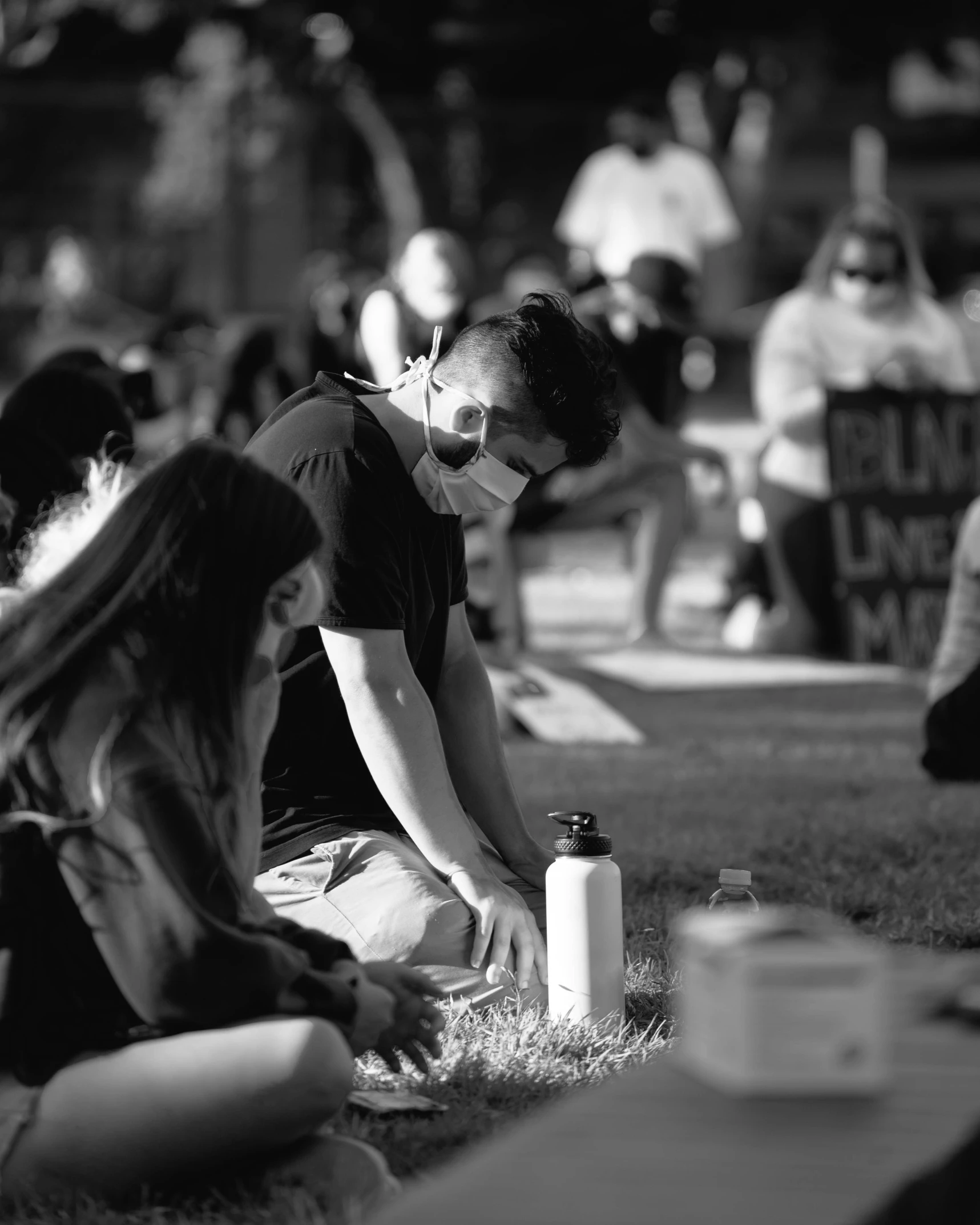 people are gathering on the grass as one is pouring water