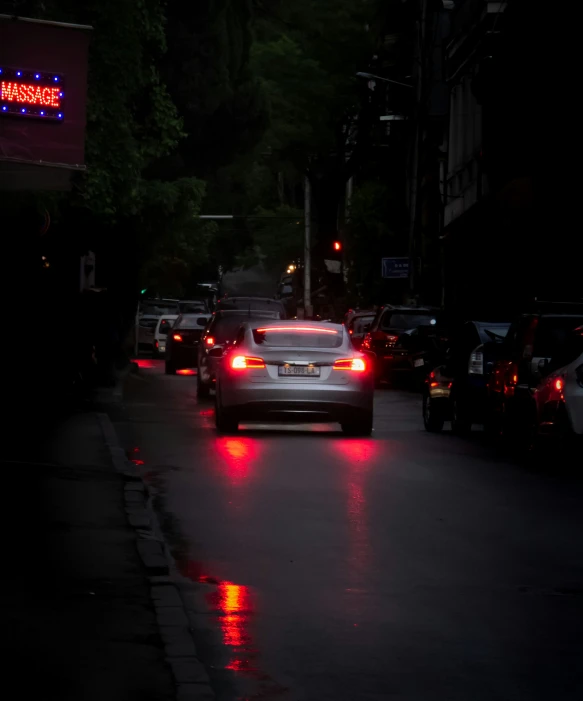 several cars driving down a street at night