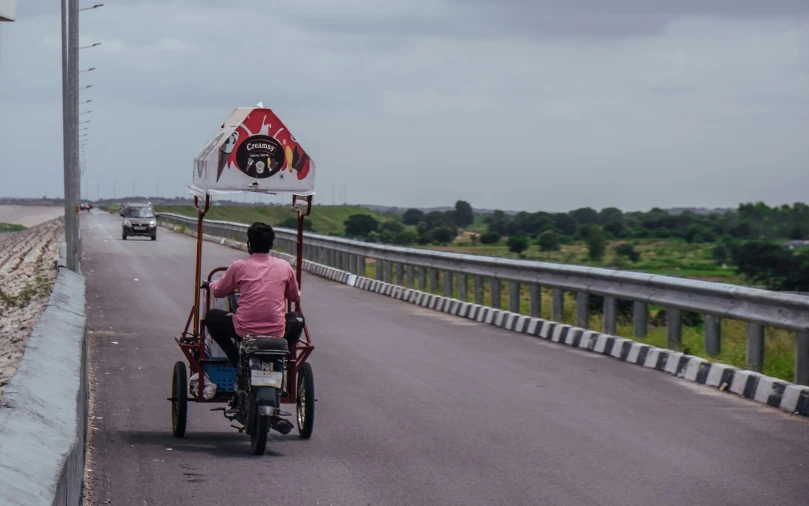 a man drives an electric vehicle with a sign on top