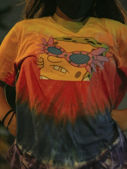 a woman with a yellow shirt and tie dye t - shirt that has a picture of a simpsons in sunglasses