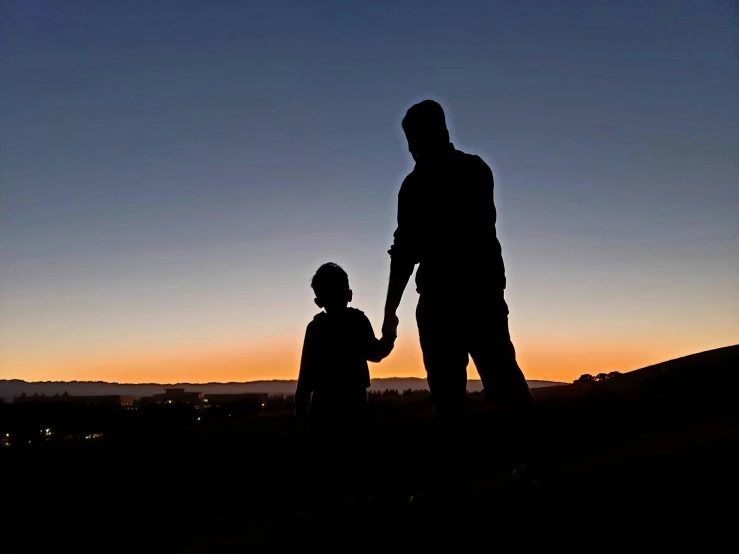 two people in silhouette standing holding hands as the sun sets