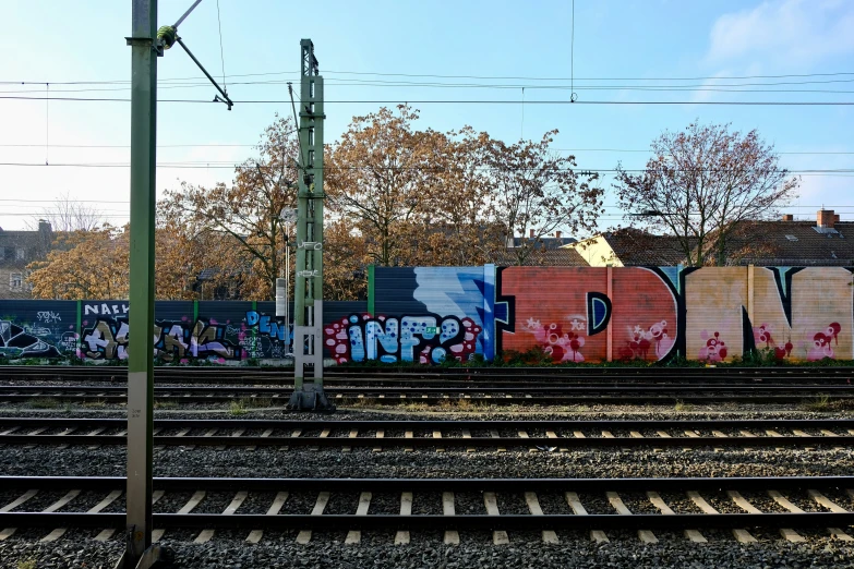 a train track with a graffiti writing wall in the background