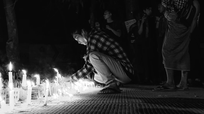 a man kneeling down on a floor covered with lots of candles