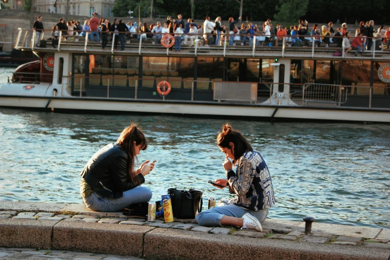 two women on a boat on the water with people standing next to the boat