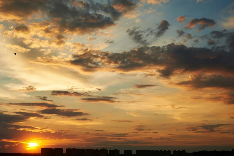 a sunset on the horizon with an airplane in flight