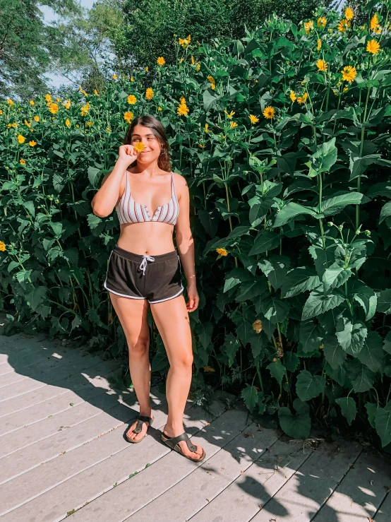 the girl is standing by the sunflowers and eating