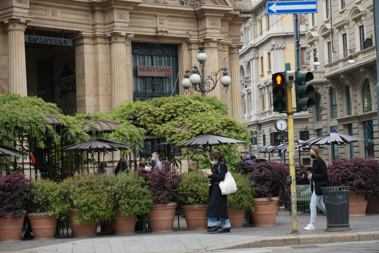 a group of people walking down a sidewalk by flowers