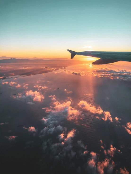 a plane flying over clouds during sunset as seen from inside