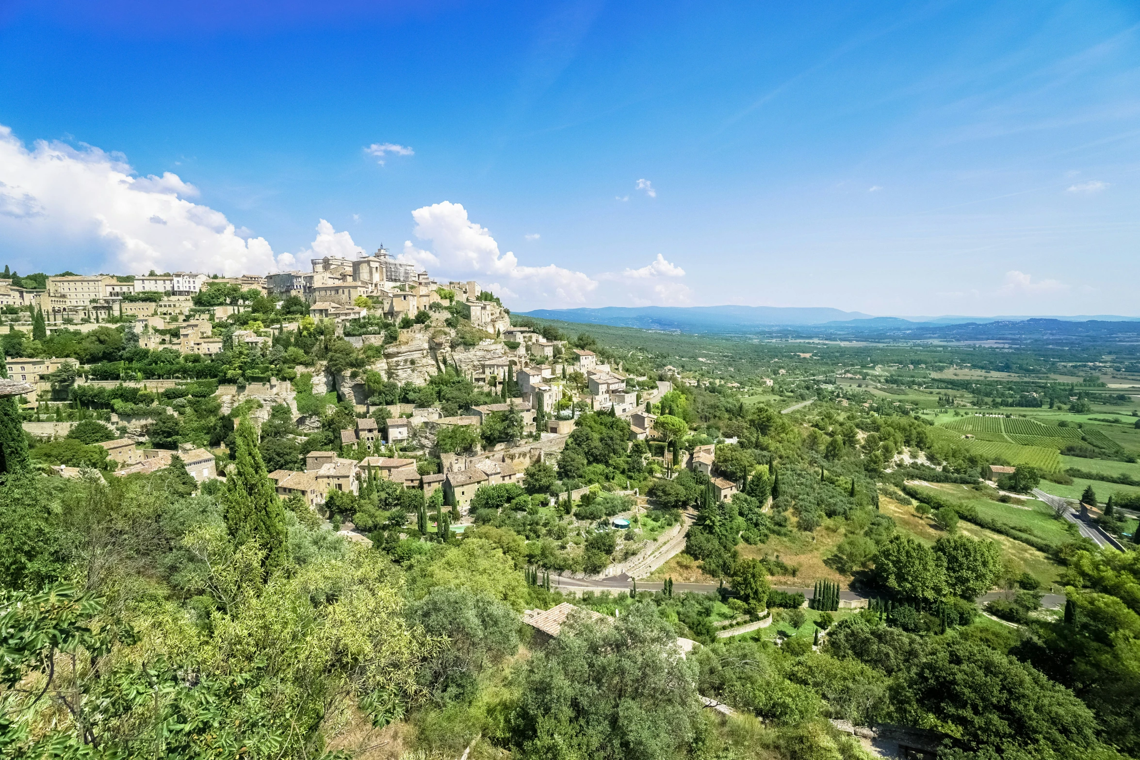 aerial view of a rocky hill with trees, bushes and fields