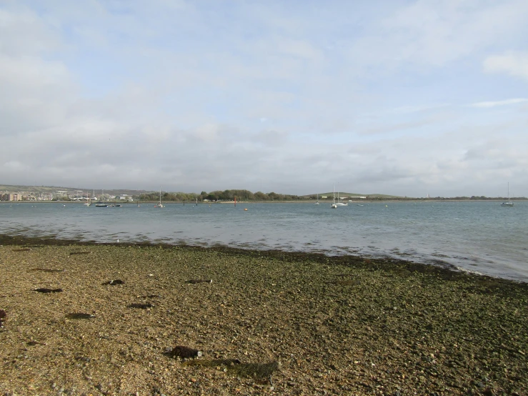 an empty beach has a body of water and boats in the distance