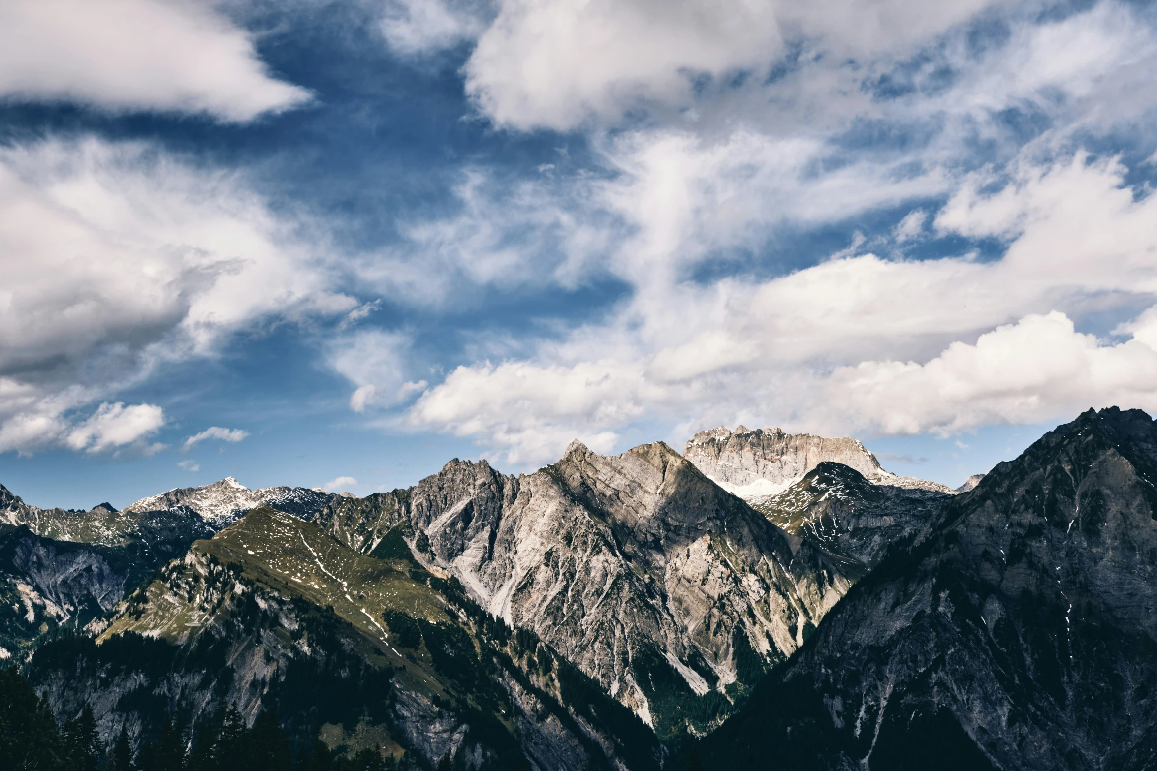 the mountains are covered in snow under some clouds