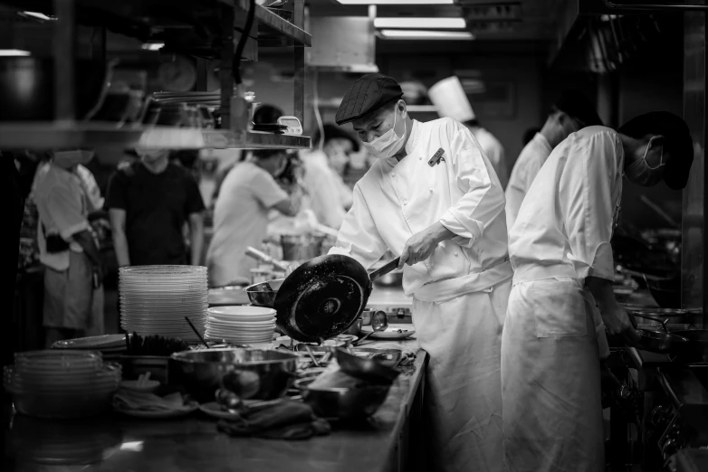 a chef cooks in a restaurant kitchen while some people watch