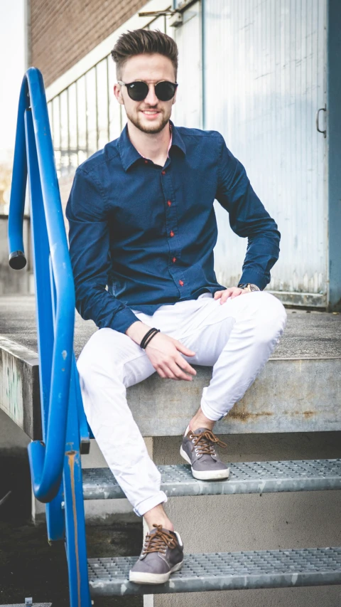 a man sitting down while he is wearing sunglasses