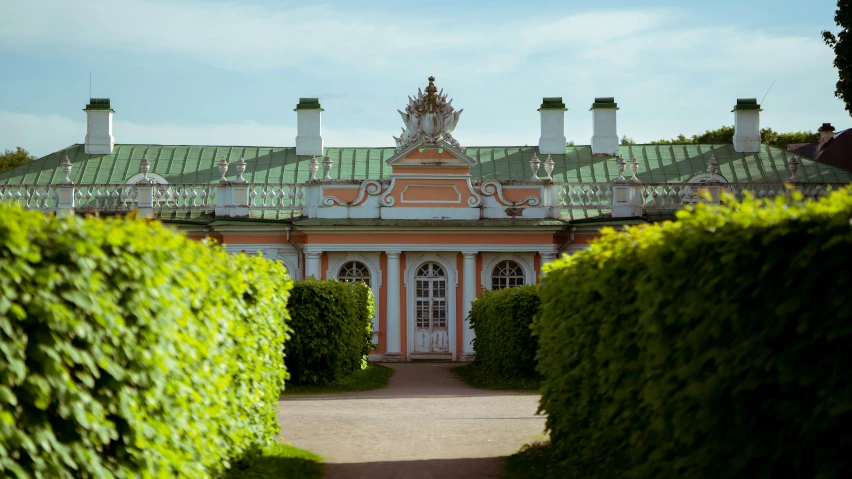 an ornate building with green topiary on a sunny day