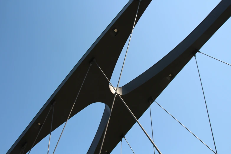 looking up at an almost - cloudy blue sky from inside a bridge