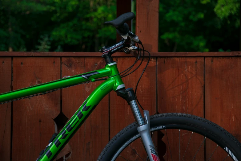 a green bicycle in front of a fence